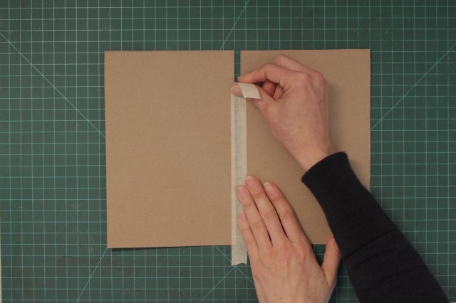 Use a piece of masking tape to connect the two pieces of cardboard leaving about a half inch in between them