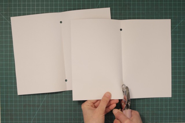 Punch corresponding holes on the folded blank sheets of paper