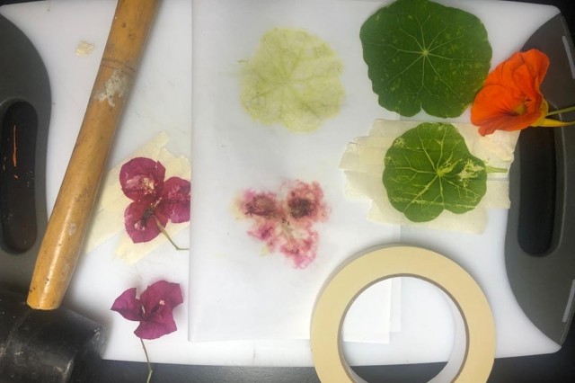 Close-up of materials including flowers, leaves, masking tape, and mallet
