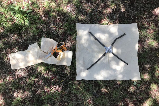 Coloca la &quot;X&quot; sobre la tela de modo que la punta de cada palito coincida con una esquina de la tela, cortando tu tela de modo que quede un poquito más grande que la &quot;X&quot;.