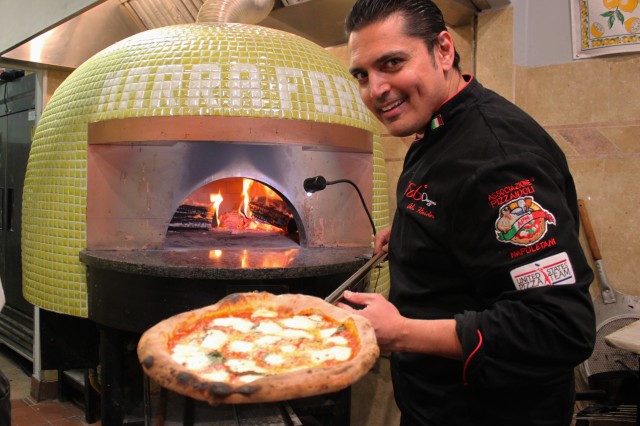 Pan standing in front of pizza oven with pizza