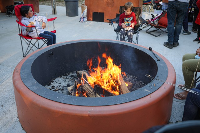 Two children in camping chairs around a fire