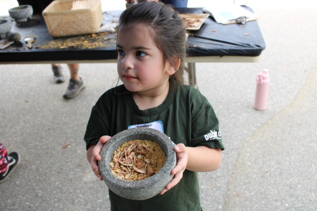girl holds mortar full of crushed acorns