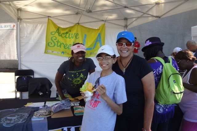 A mom and daughter standing on front of a promotional booth at a bicycle event.