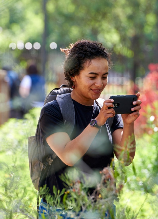 girl taking picture with phone in nature gardens