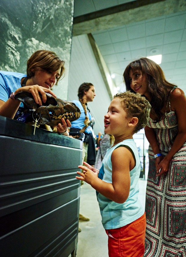 Family admiring direwolf skull with gallery interpreter at La Brea Tar Pits