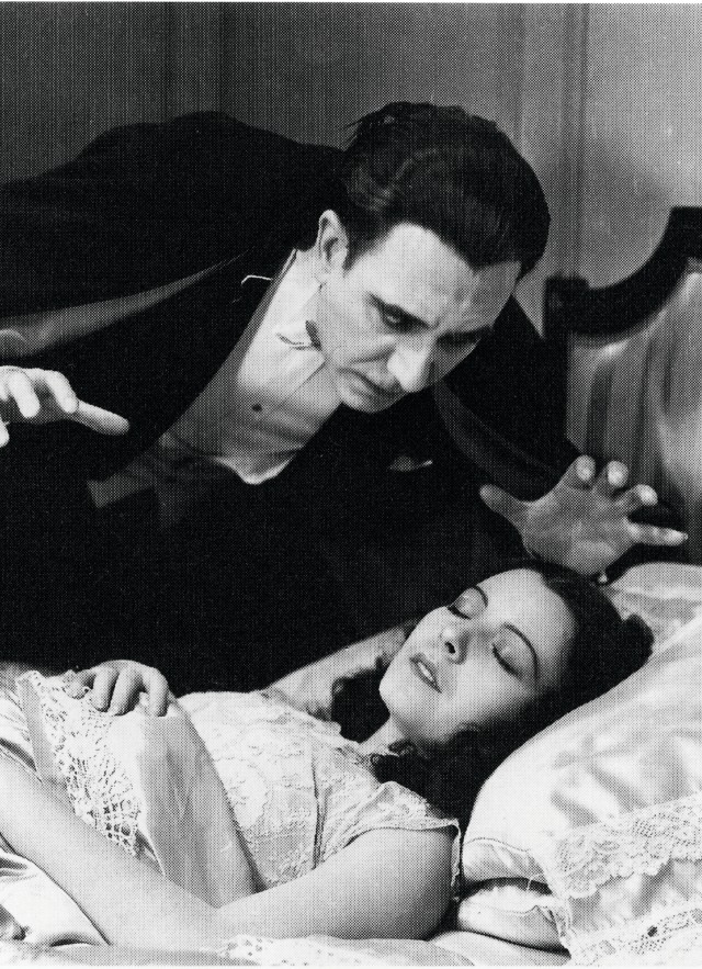 Still image from horror film Dracula. The vampire leans ominously over a sleeping woman.