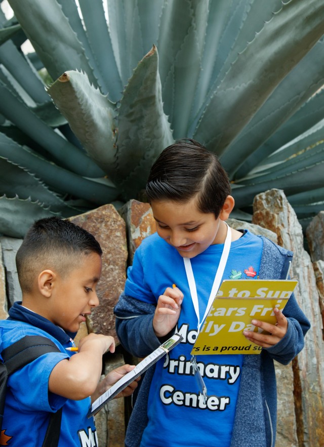 Two grade-school age students writing while in nature