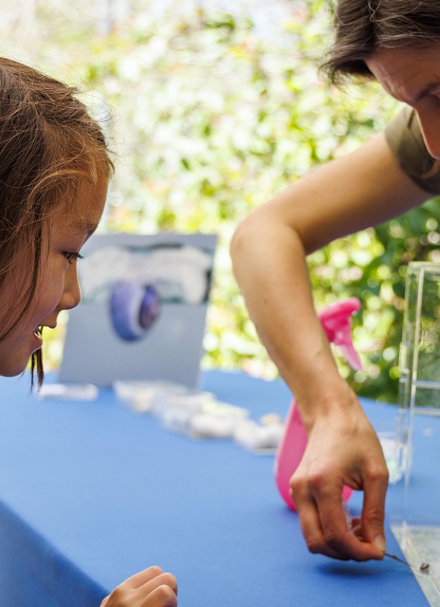 Dr. Jann Vendetti showing a child a specimen on a table during Earth Day 2023