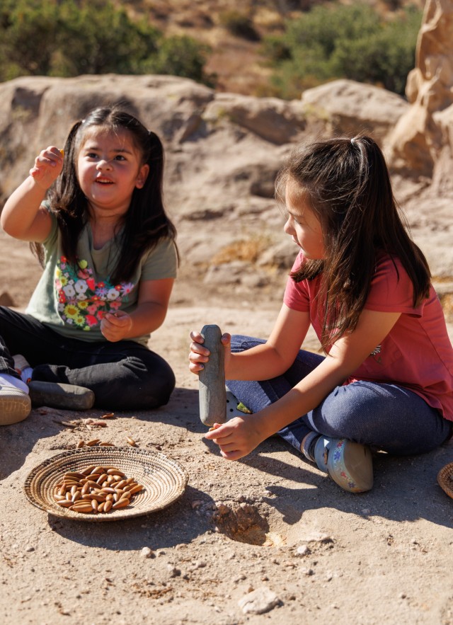 Two Fernandeño Tataviam Band of Mission Indian children grinding acorns