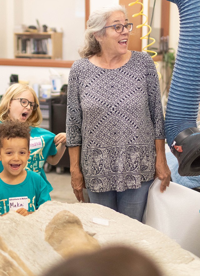 Maureen Walsh and children standing around a table with a skeletal specimen