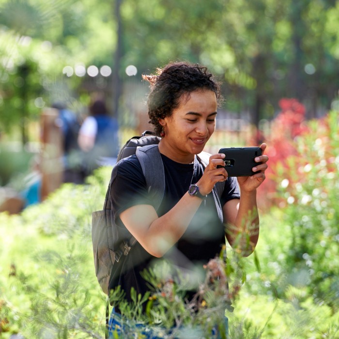girl taking picture with phone in nature gardens