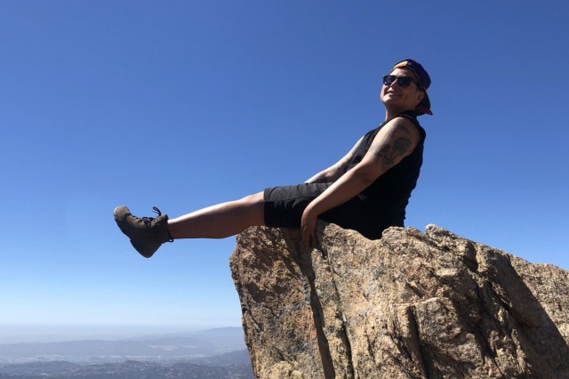 Mari Moreno sitting on a rock in the hills over Los Angeles