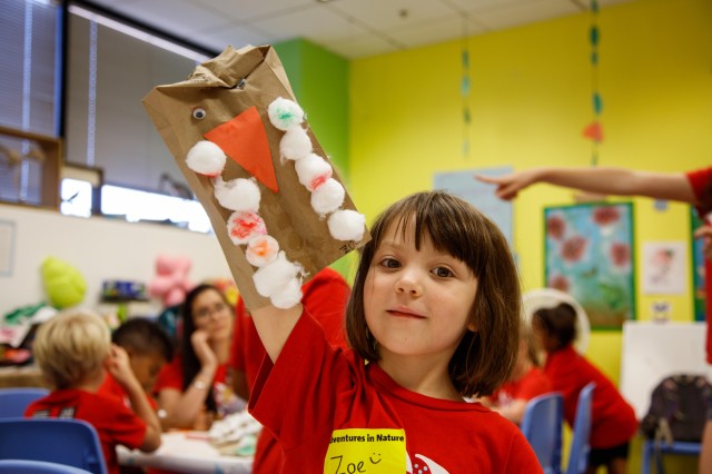 Little girl holding up bird craft. 