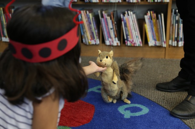 A young child interacts with a squirrel puppet at a Nature Day event.
