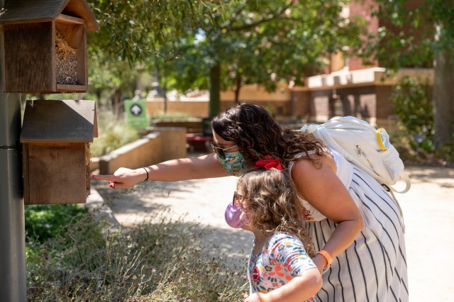 Member mother and daughter looking at bug hotel in nature gardens