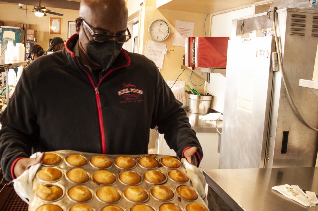 Terry Dulan pulling warm cornbread muffins from the oven.