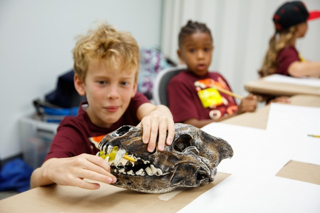 a young boy holds a skull of a dire wolf in two hands