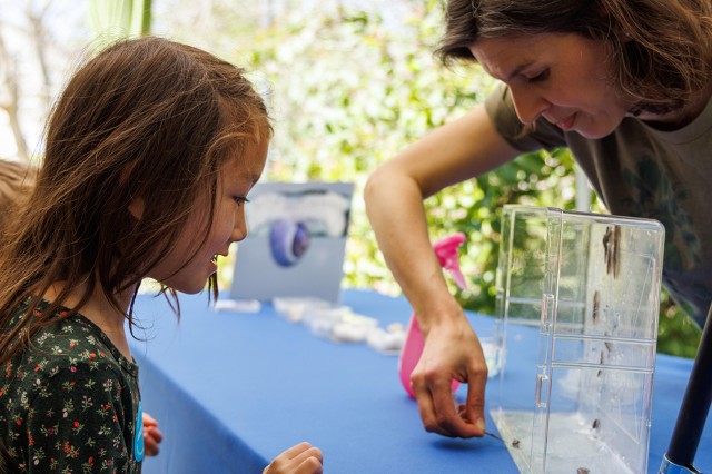Dr. Jann Vendetti showing a child a specimen on a table during Earth Day 2023