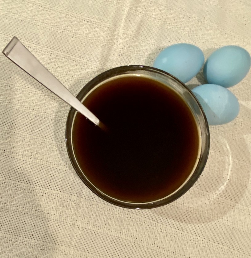 bowl of coffee with three blue eggs next to it