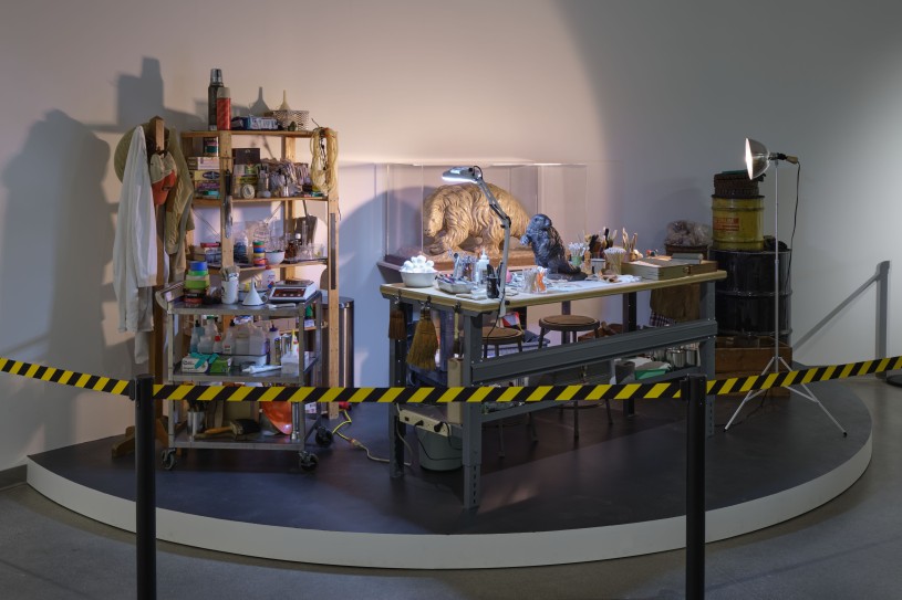 A paleontological prep lab with giant sloth maquettes table and various excavation tools all behind a caution tape 