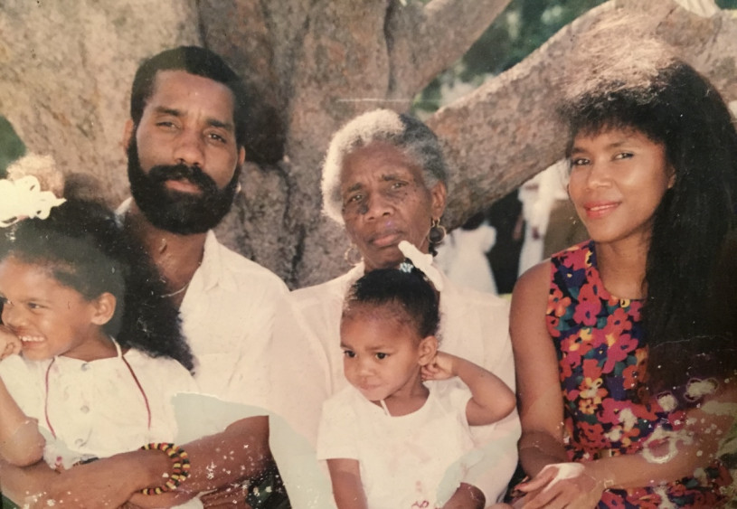 A man holds his young daughter with an older woman and younger woman holding another young girl