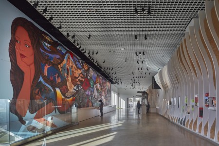 Mural of a woman holding her head in her hand, with colorful vignettes in her hair